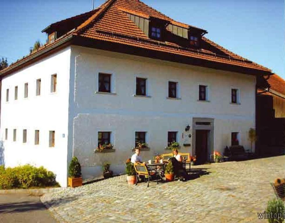 格拉弗瑙Ferienhof Aiginger的两人坐在白色建筑前的椅子上