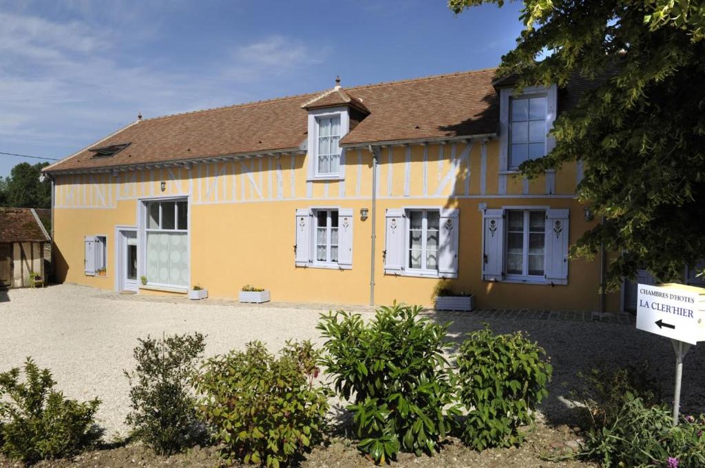 CléreyLA CLER'HIER的黄色的房子,有白色的窗户和车道