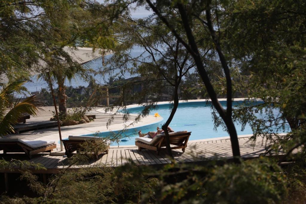 曼克拉海洋美景度假屋的两人坐在游泳池旁的长椅上