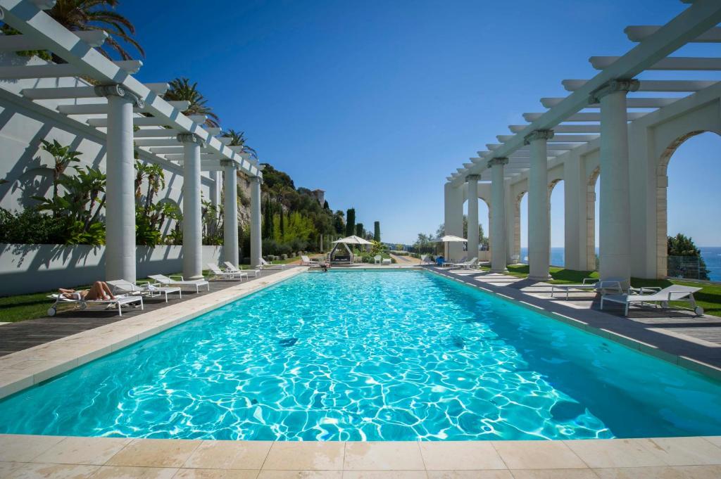 尼斯Luxury Apartment Palais Maeterlinck的拥有白色柱子和蓝色水的游泳池