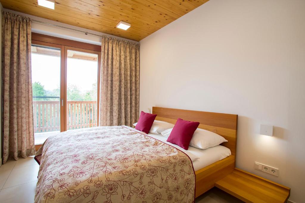 加姆利茨莫尔罗思尔公寓酒店的一间卧室配有一张带红色枕头的床和一扇窗户