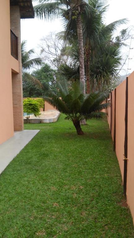 卡拉瓜塔图巴Refugio Massaguaçu的一座绿色庭院,旁边是一座建筑,旁边是棕榈树
