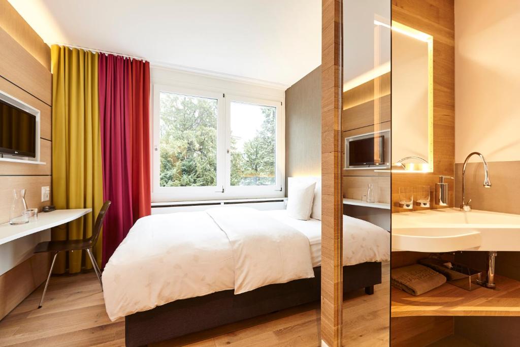 巴塞尔斯坦恩斯坎泽城市酒店的酒店客房设有床、水槽和窗户。