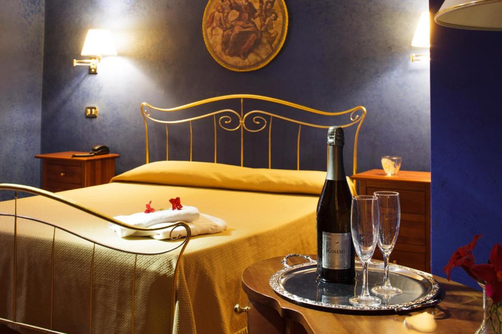 VeroliHotel Relais Filonardi的一间卧室配有一张床,桌子上放着一瓶葡萄酒