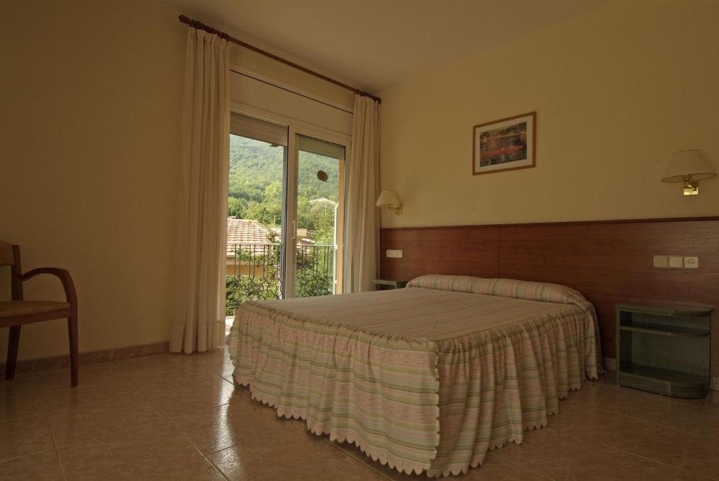 圣费柳-德帕利亚罗尔斯方达芬耐酒店的一间卧室设有一张床和一个大窗户