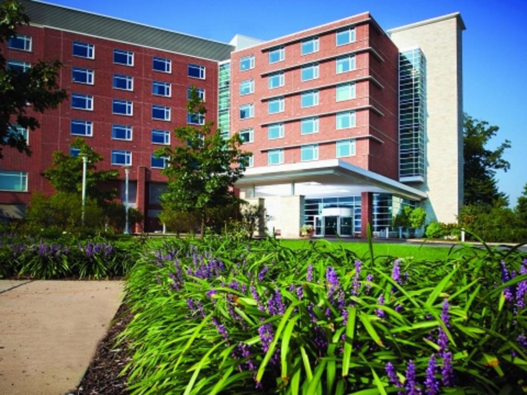 州学院宾州斯塔特酒店及会议中心 的一座建筑前方有紫色花的建筑