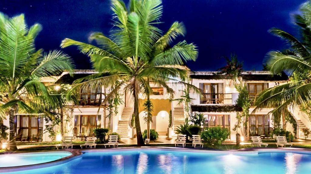 南威My Blue Hotel Zanzibar的夜间带游泳池和棕榈树的度假村