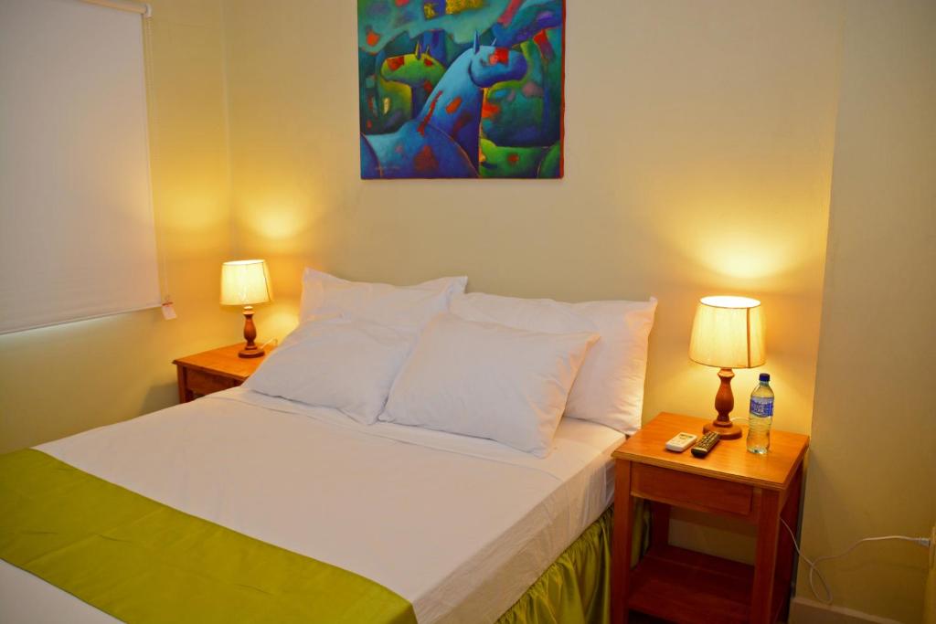马那瓜Hotel Santa Martha的一间卧室配有一张带两盏灯和一幅画的床铺