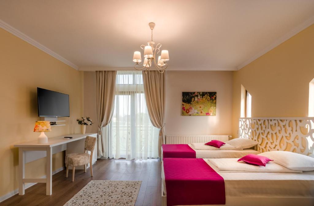 坎皮纳Seva Hotel Health Club的酒店客房设有两张床、一张书桌和一个吊灯。