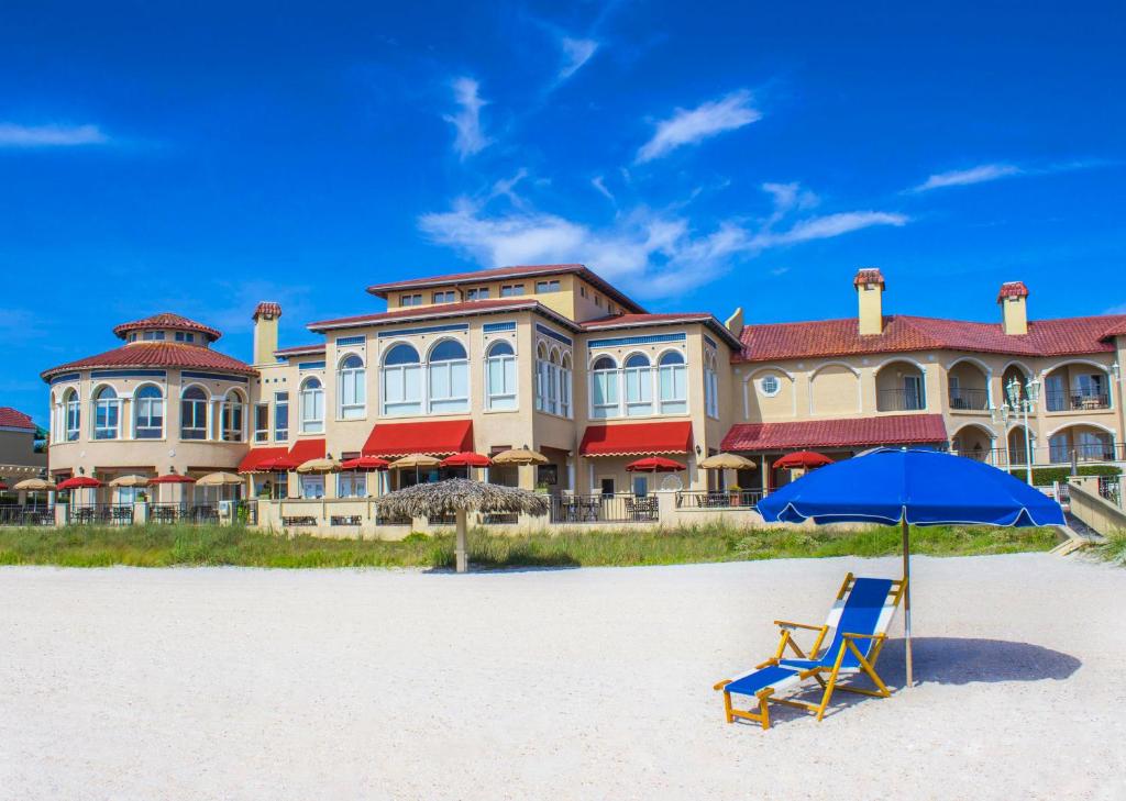 庞特韦德拉比奇蓬特韦德拉海滩旅馆及俱乐部的房屋前的海滩上摆放着一把椅子和一把遮阳伞