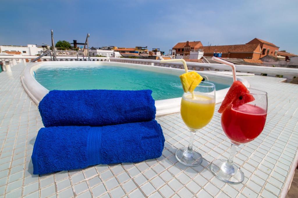 卡塔赫纳三旗酒店的一张桌子,旁边是游泳池,有两杯饮料