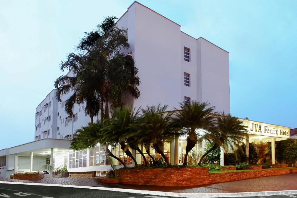 乌贝兰迪亚JVA Fenix Hotel的一座白色的建筑,前面有棕榈树