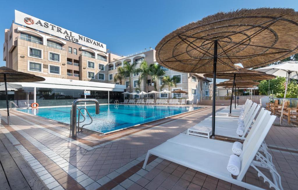 埃拉特Hotel Astral Nirvana Club- Half Board的带椅子和遮阳伞的游泳池