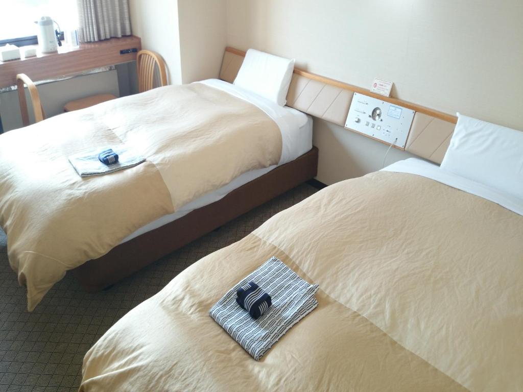 大崎市古川山丘酒店的两张位于酒店客房的床,上面装有两袋