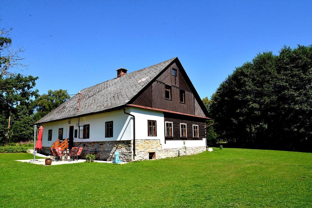 克拉利基Ubytování Chalupa的一块大白色谷仓,在田野上有一个黑色的屋顶