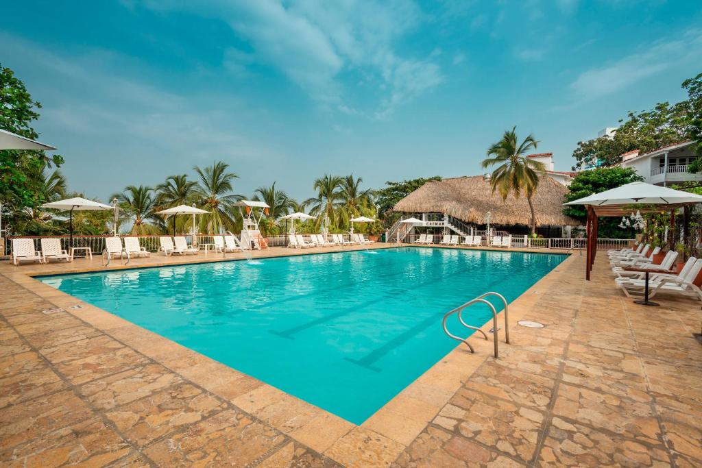 圣玛尔塔加连得可麦仑酒店 - 全包的度假村的游泳池配有椅子和遮阳伞