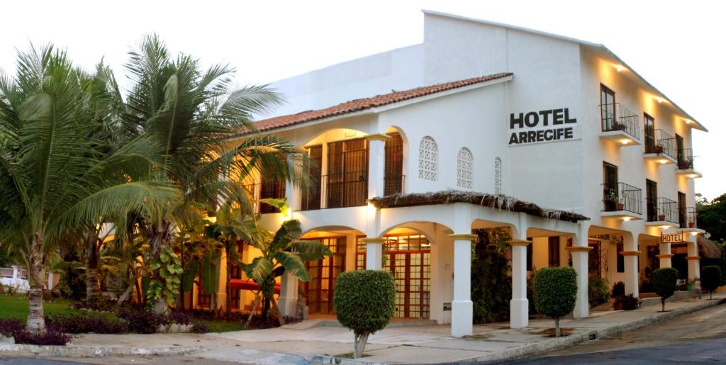 圣克鲁斯华特库Hotel Arrecife Huatulco Plus的前面有棕榈树的酒店入口