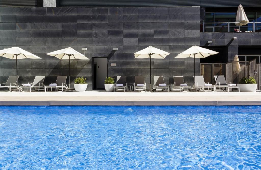 马德里伊鲁尼阿垂姆康福特尔酒店的酒店游泳池设有椅子和遮阳伞