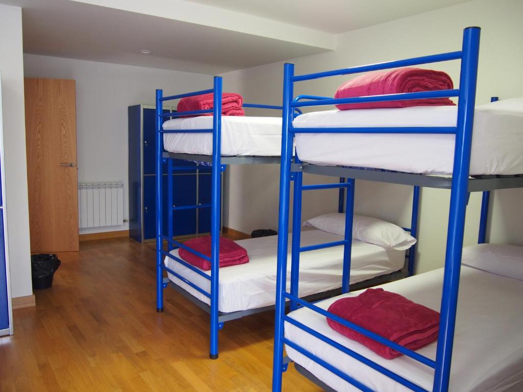苏维里Albergue Segunda Etapa的客房配有蓝色双层床和红色枕头。