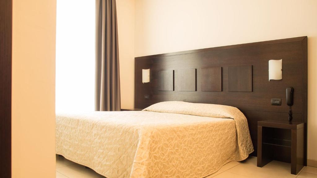 格罗塞托艾克雷斯皮酒店的一间卧室配有一张大床和木制床头板