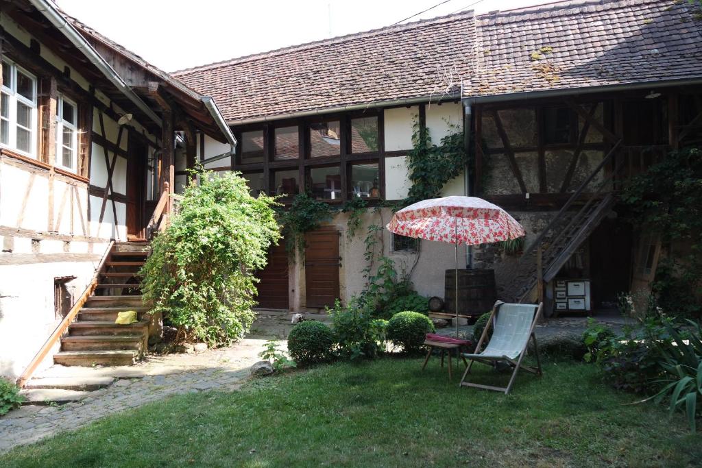 巴尔Le temps des cigognes的院子里的房屋,配有椅子和遮阳伞