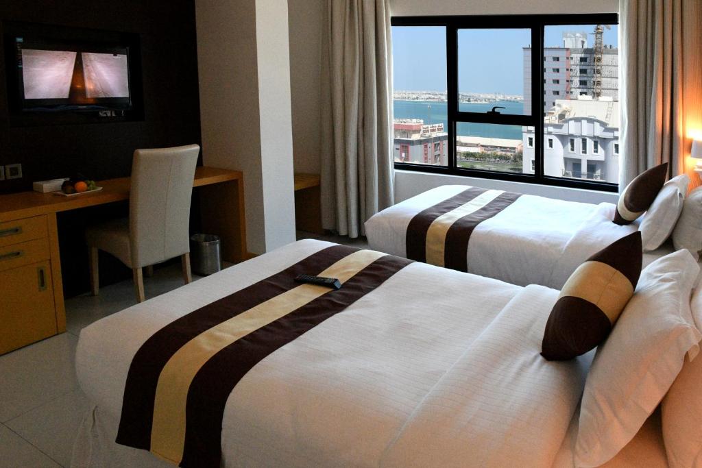 麦纳麦Al Olaya Suites Hotel的酒店客房设有两张床和大窗户。