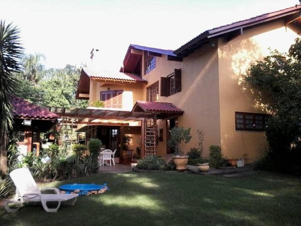 本图贡萨尔维斯Casa das Palmeiras + Quiosque的房屋设有庭院、椅子和桌子