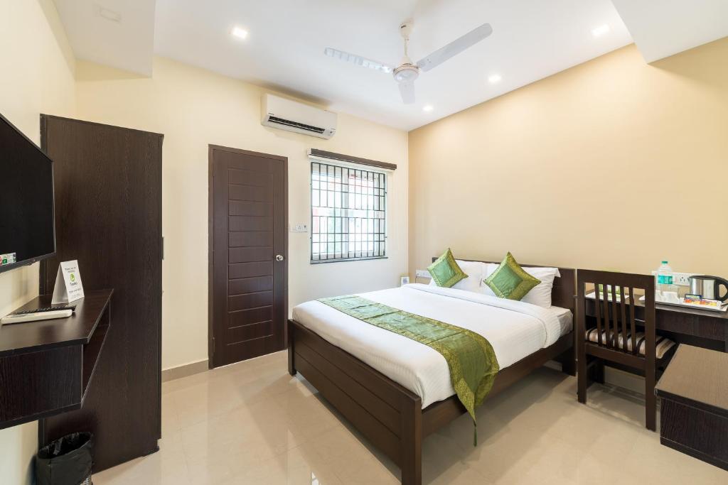 钦奈Treebo Adin Residence Chennai Trade Centre的一间卧室配有一张床、一张书桌和一台电视