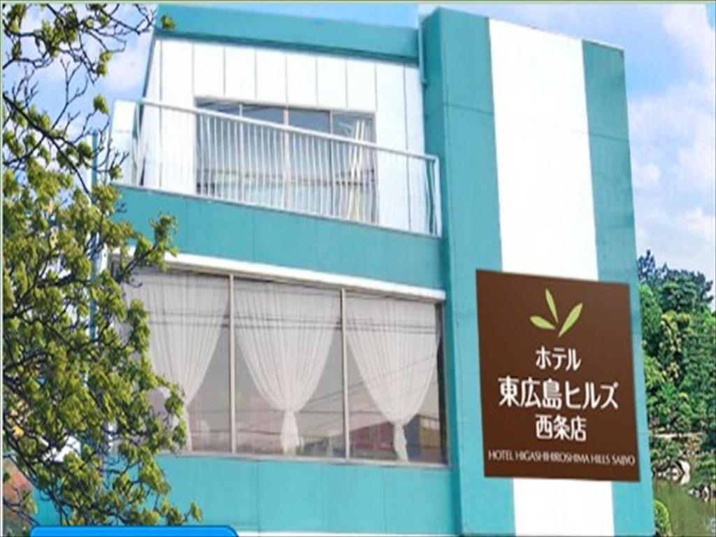 东广岛市东广岛西条山酒店的蓝色和白色的建筑,前面有标志