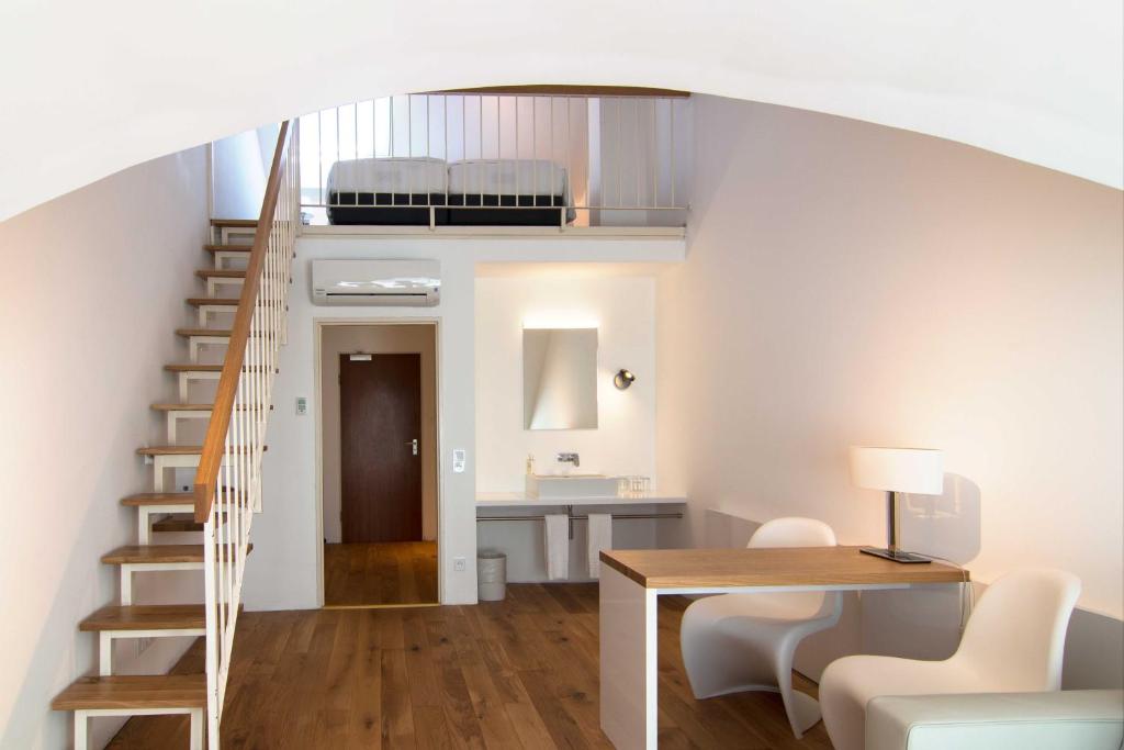 慕尼黑Downtown Vi Vadi Hotel的一间带楼梯的客厅和一间带桌子的房间