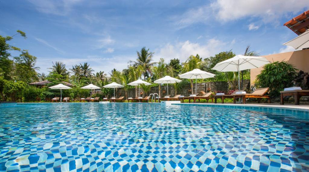 富国Elwood Premier Resort Phu Quoc的度假村的游泳池,配有遮阳伞