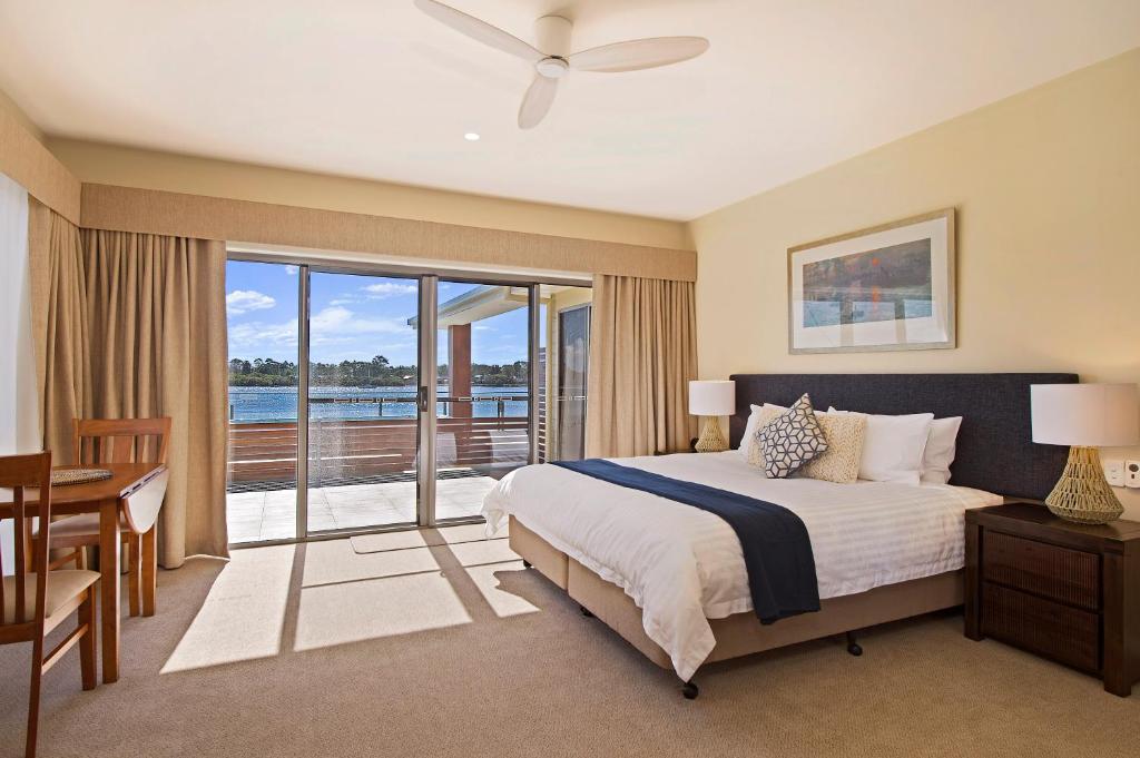 麦夸里港Ana Mandara Luxury Retreat的一间带一张床和一张书桌的卧室以及一个阳台