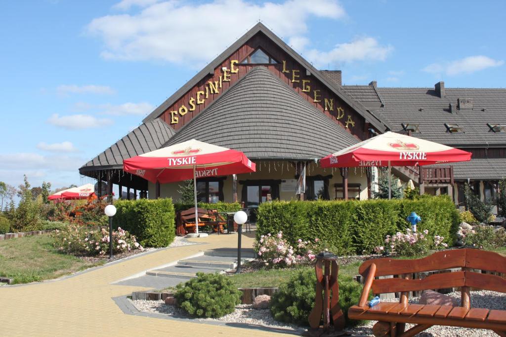 WyszogródGościniec Legenda的一间设有遮阳伞的餐厅,并在餐厅前面设有长凳