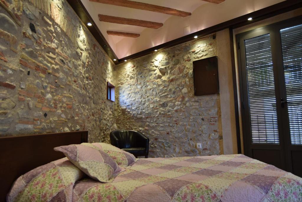 赫罗纳昆达罗之家酒店的石墙卧室配有一张床和一把椅子