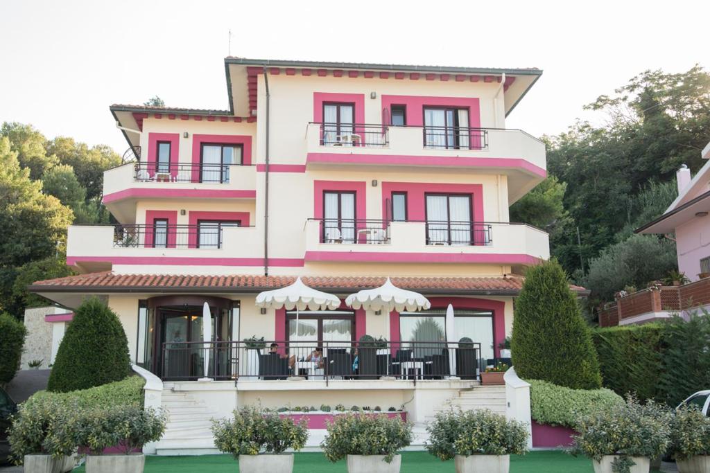 福萨切西亚莱万特酒店的粉红色和白色的建筑,前面有灌木丛