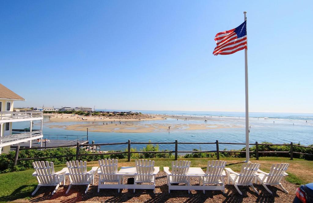 奥甘奎特Sea Chambers的一组白色椅子和一盏美国国旗和一个海滩