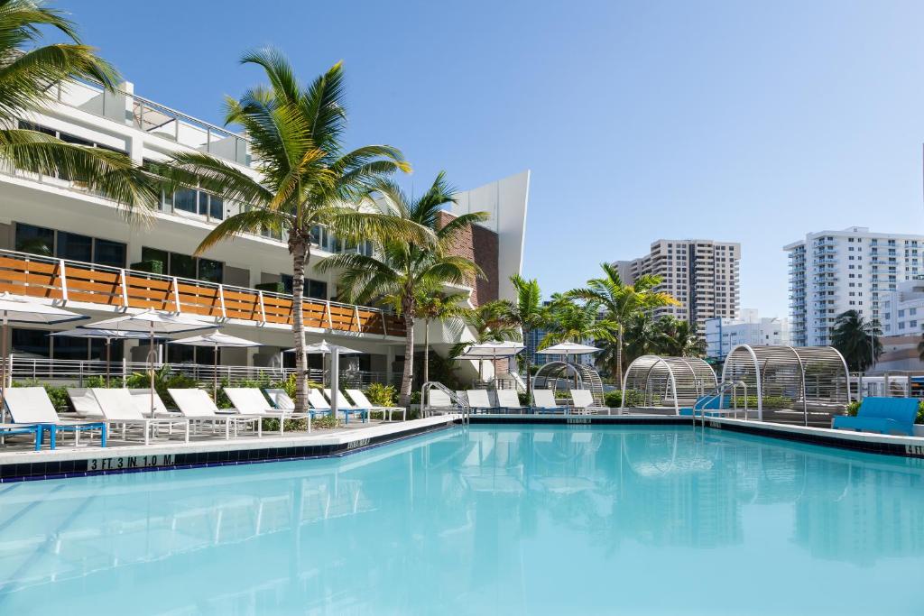 迈阿密海滩希尔顿逸林盖茨南海滩酒店的一个带椅子和棕榈树的大型游泳池