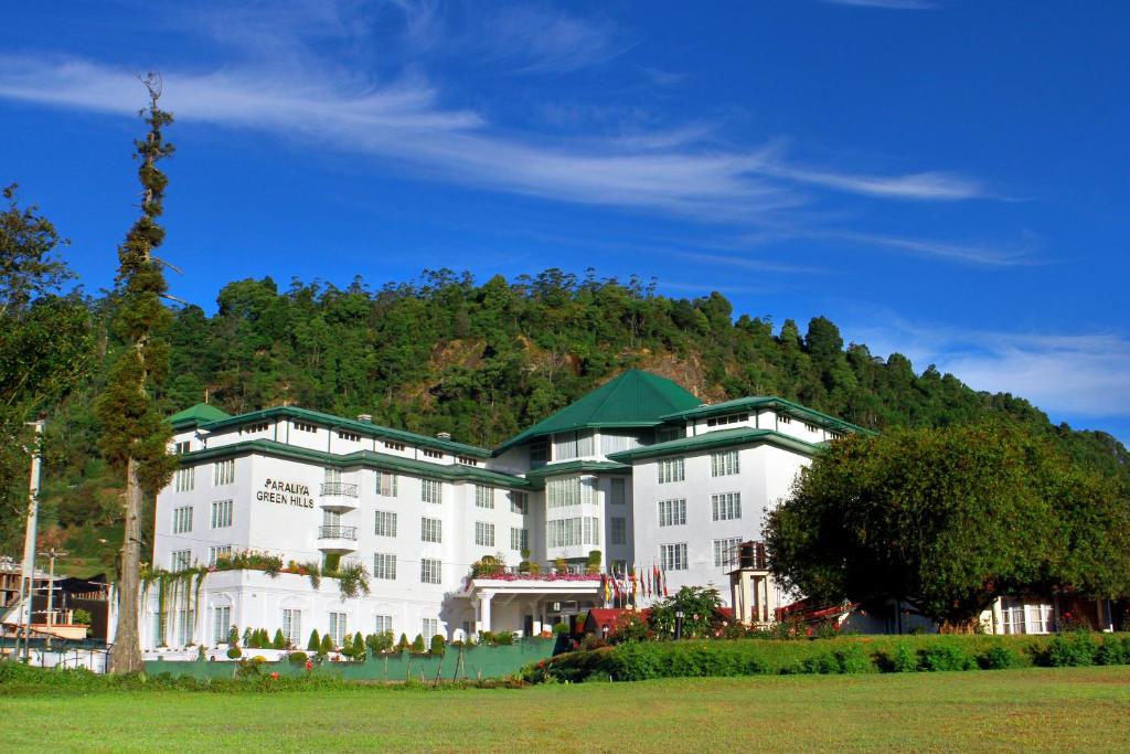 努沃勒埃利耶阿拉利亚绿山酒店的一座白色的大建筑,背景是一座山