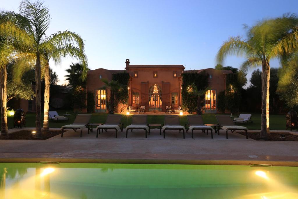 马拉喀什Villa Jannah的棕榈树和游泳池的房子