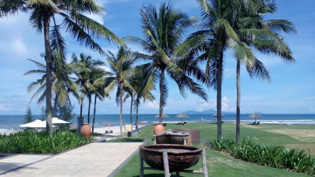 岘港Ocean Apartment Spa & Golf Danang的棕榈树公园和海滩