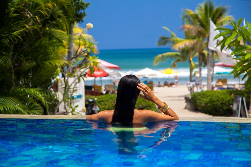 勒吉安Away Bali Legian Camakila Resort的坐在海滩旁游泳池里的女人