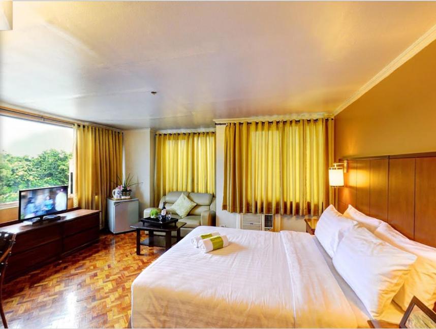 马尼拉企业酒店的酒店客房设有一张大床和一台电视。