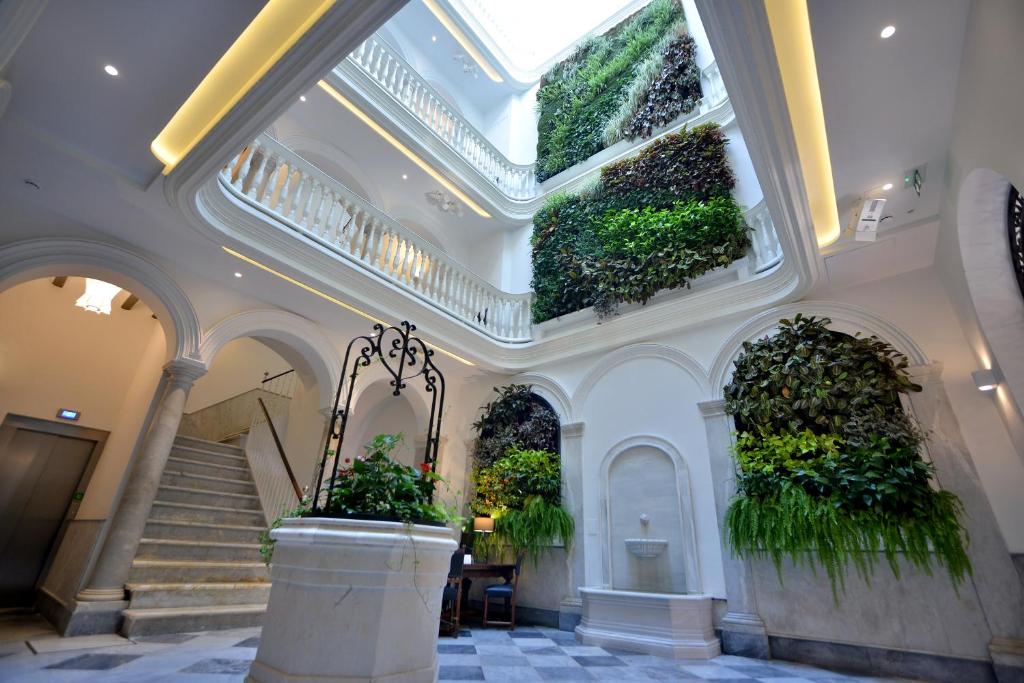 加的斯El Armador Casa Palacio by Luxury Suites Cádiz的一座种植了植物的建筑,位于天花板和楼梯上