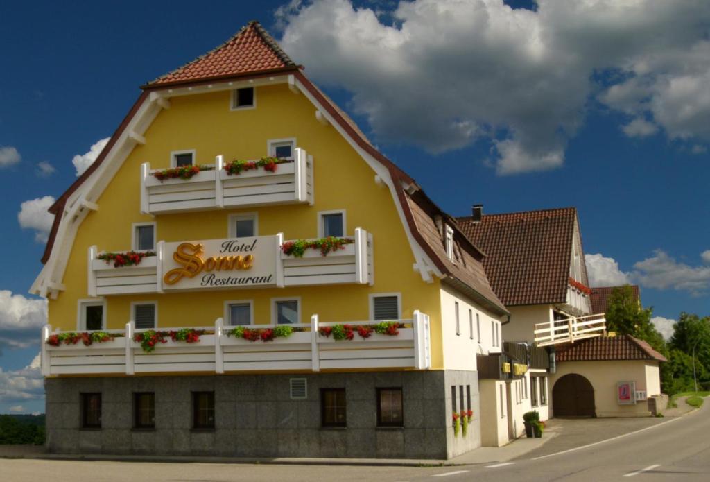 Rudersberg索奈酒店及餐厅的一座黄色的大建筑,设有白色的阳台和鲜花