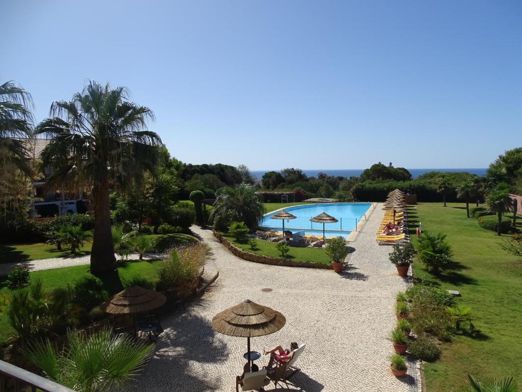 卢斯露兹马尔别墅酒店的享有带遮阳伞的游泳池和度假村的景致。