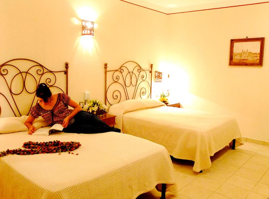 瓦哈卡市Hotel Dainzu的坐在酒店房间床上的女人