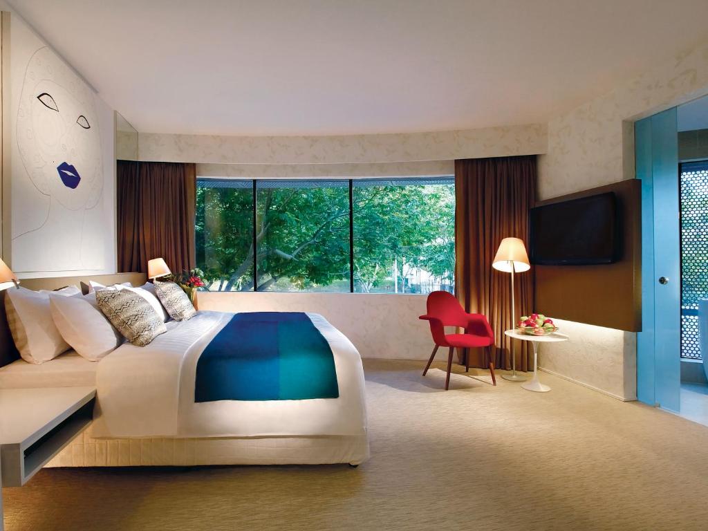 新加坡D'Hotel Singapore managed by The Ascott Limited的一间卧室配有一张大床和一张红色椅子