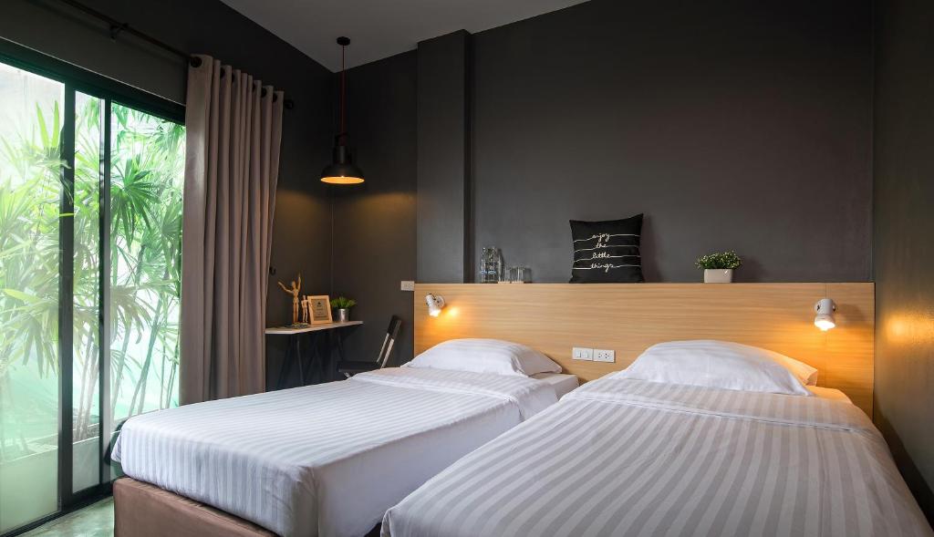 甲米镇斯瑞苏克桑特广场旅舍的一间卧室设有两张床和大窗户