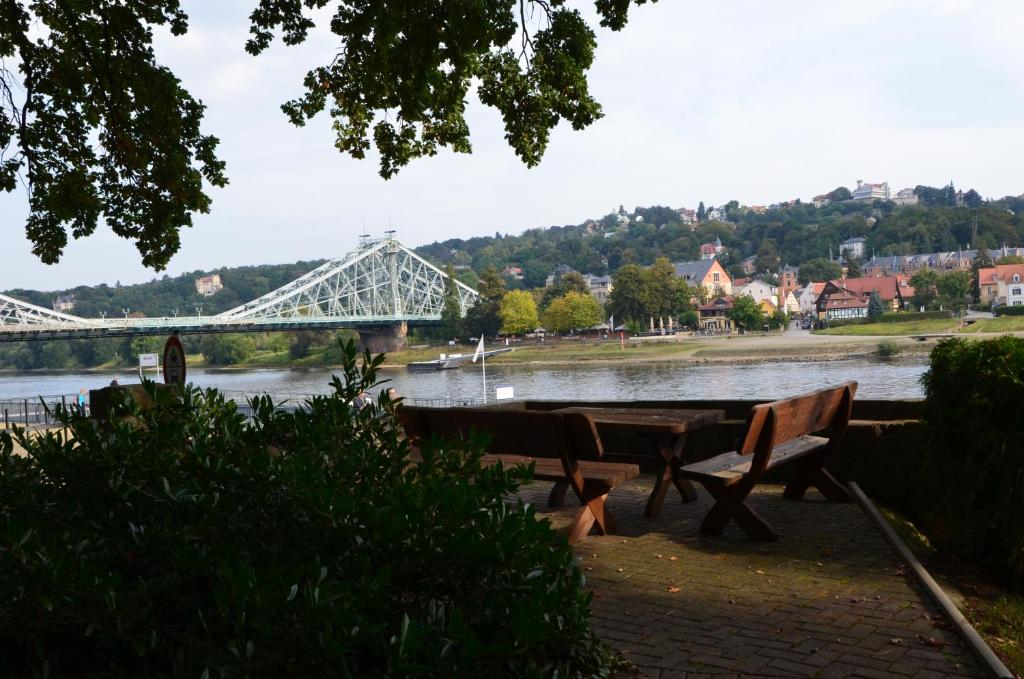 德累斯顿Ferienwohnung an der Elbe的一条有长椅和桥的河流