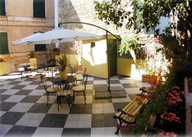 蒙特罗索阿尔马雷诗歌作家酒店的庭院配有桌椅和遮阳伞。